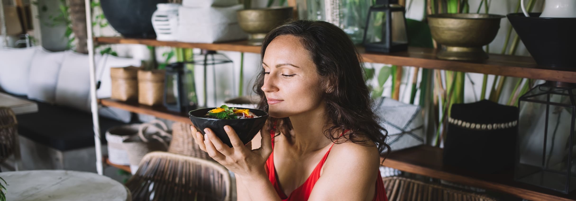 Mujer practicando alimentación consciente al observar y disfrutar un plato de comida saludable antes de comer.